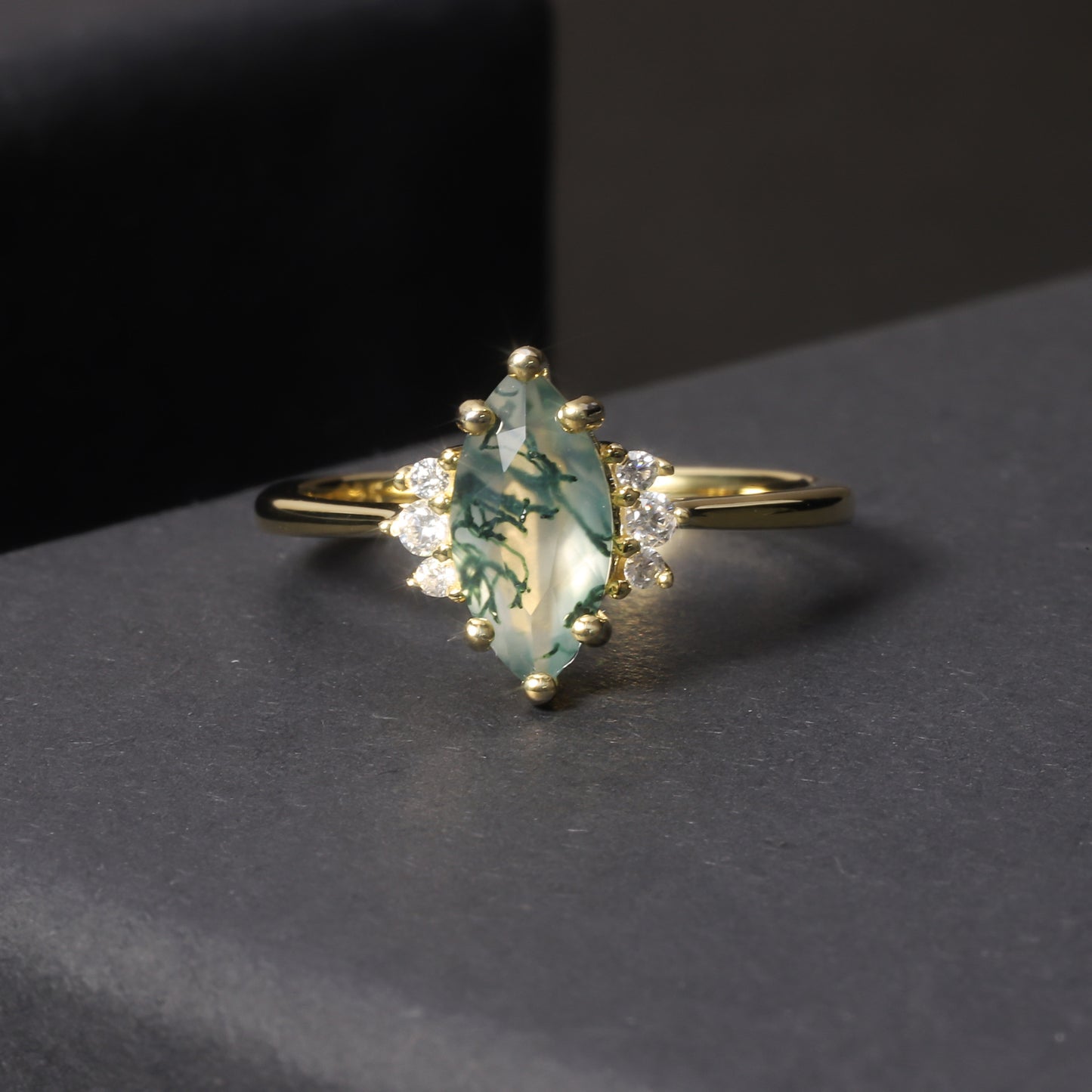 Gold ring with a green gemstone on a dark surface