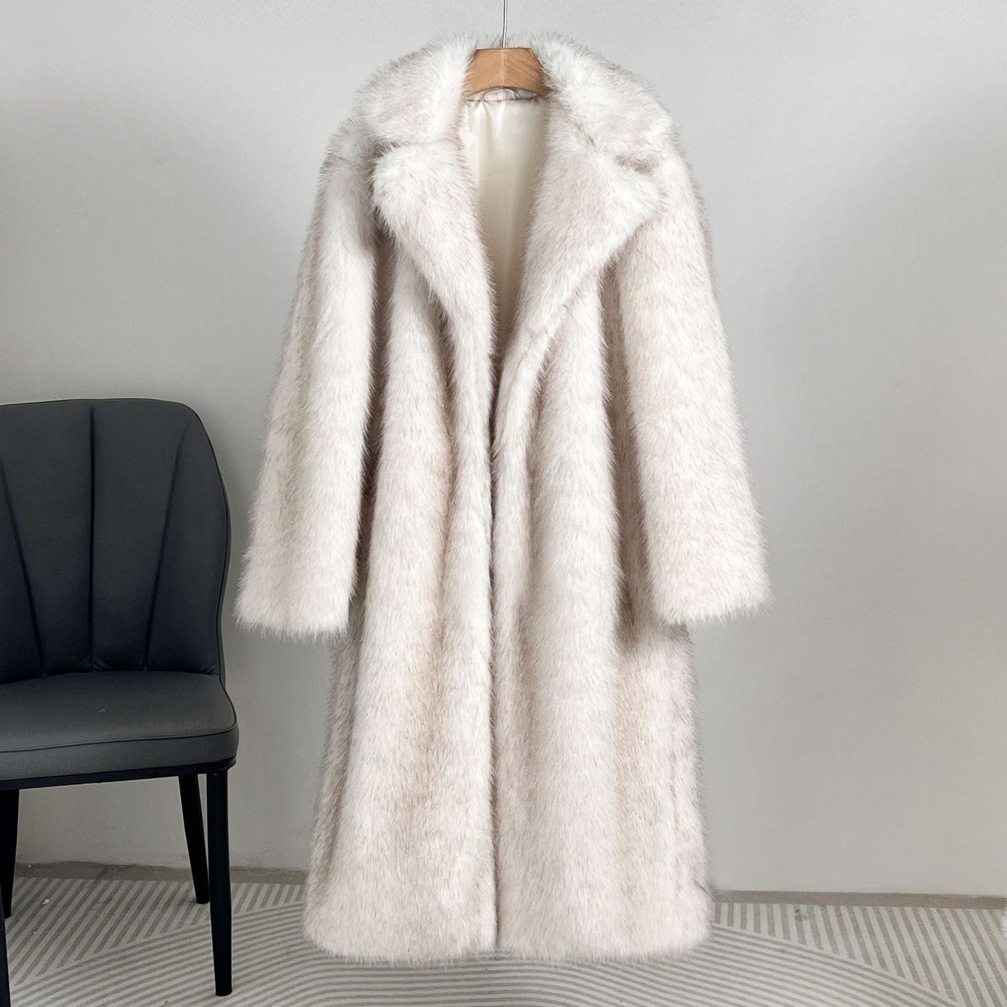 White fur coat on a hanger against a plain background