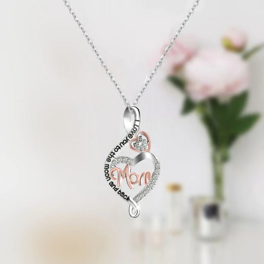 Heart-shaped pendant necklace with 'Mom' engraving on a blurred floral background