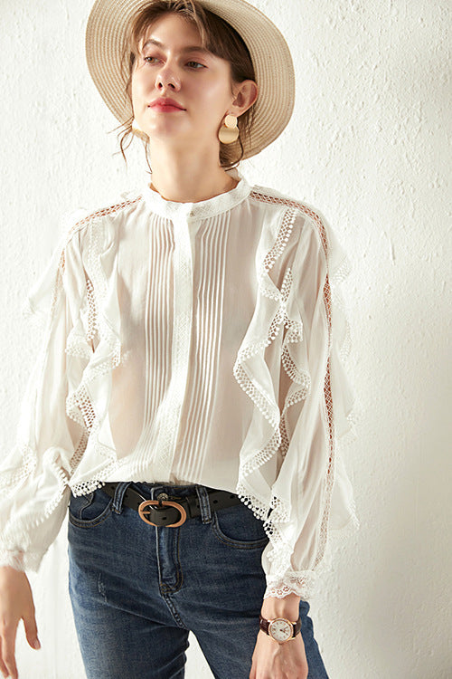 Woman wearing a white lace blouse and blue jeans against a plain background