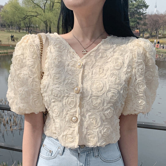 Person wearing a floral blouse with a park in the background