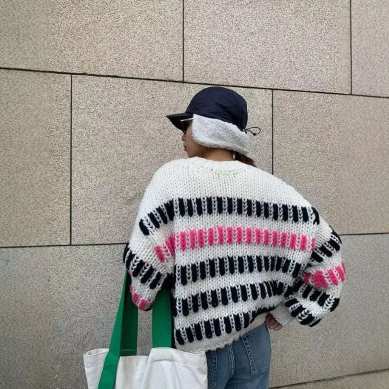 Person wearing a colorful striped sweater against a tiled wall