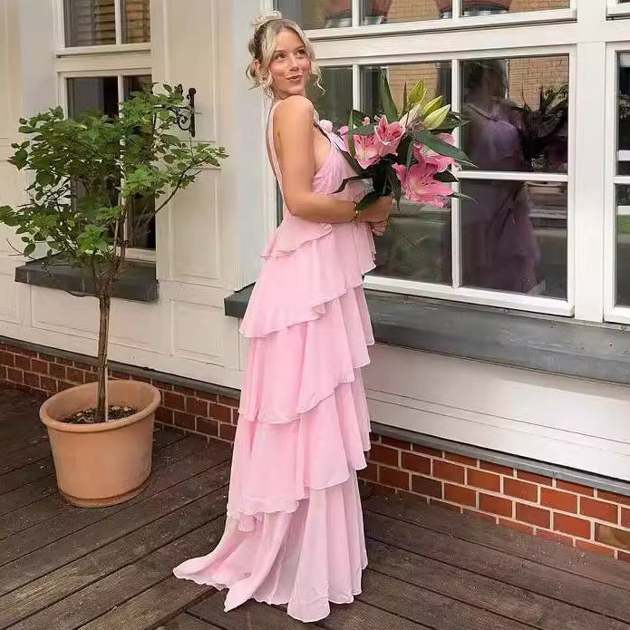 Woman in a pink dress holding flowers on a wooden deck with a building in the background