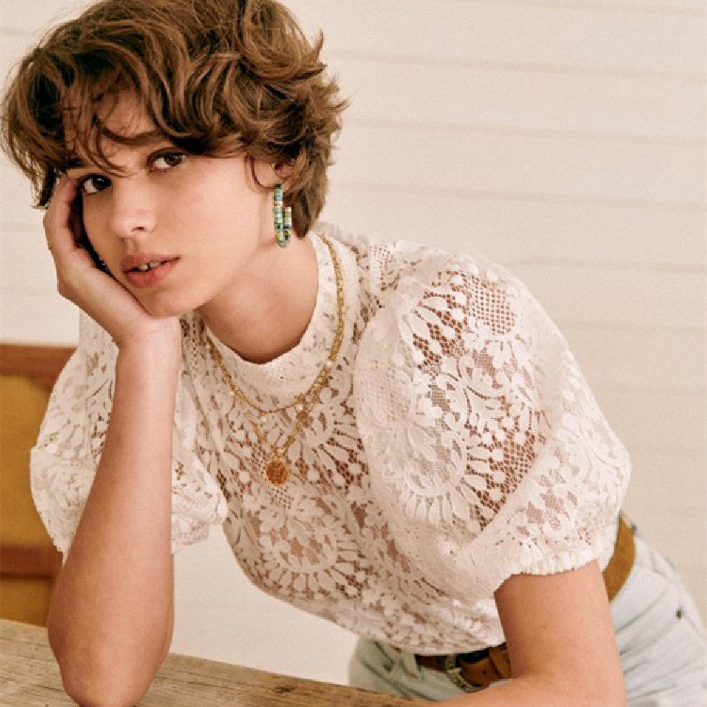 Woman wearing a white lace top with a neutral background
