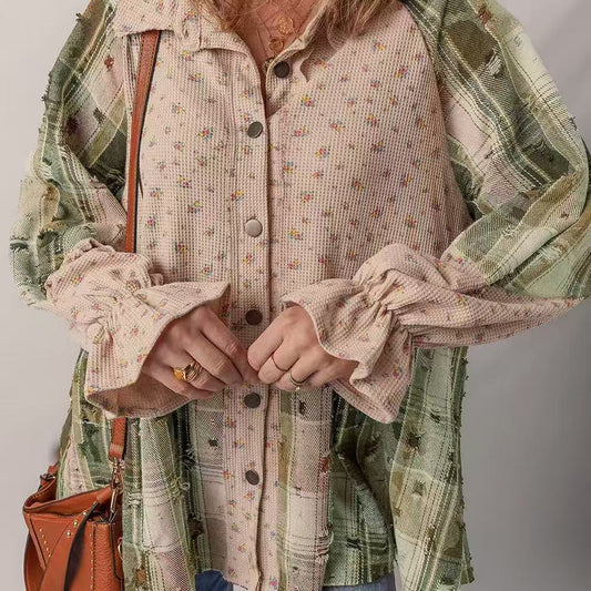 Person wearing a patterned shirt with a plaid shawl over shoulders, holding a brown leather bag.