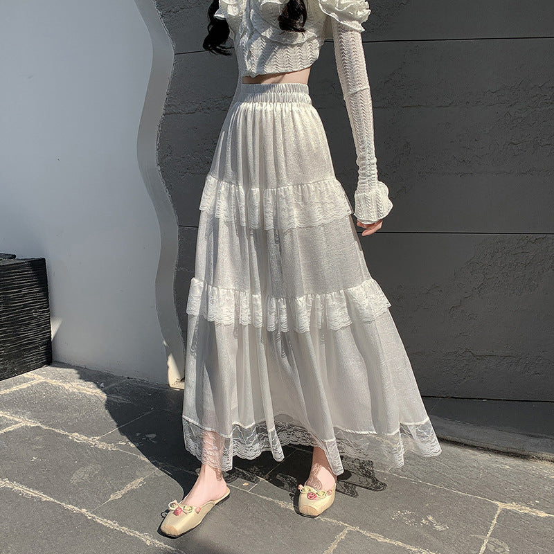 Person wearing a white lace outfit against a gray wall.