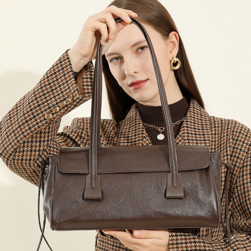 Woman holding a brown handbag against a neutral background