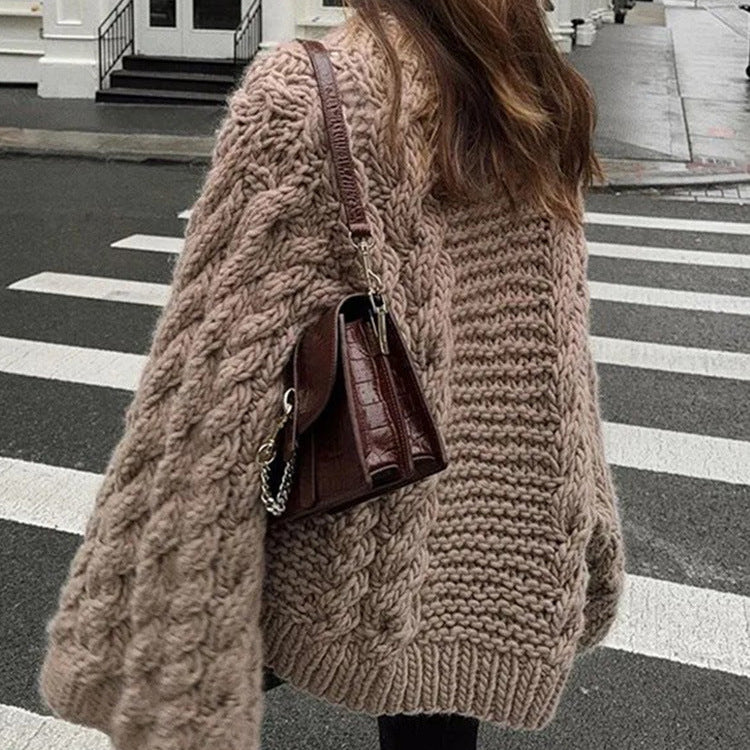 Person wearing a beige knitted cardigan on a city street