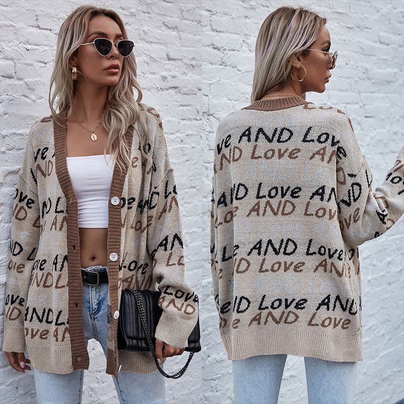 Woman wearing a cardigan with text patterns against a white brick wall.