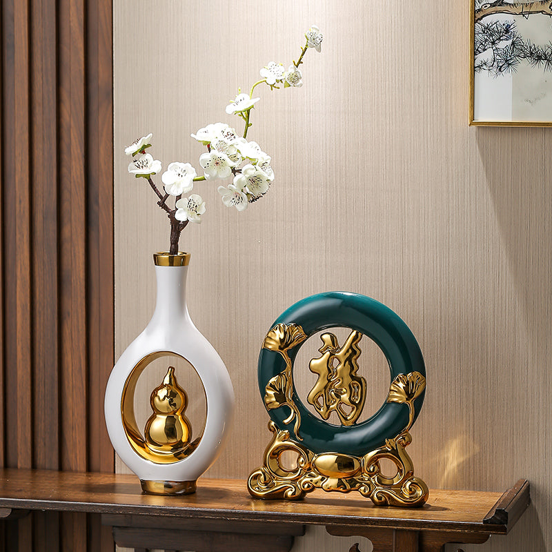 Decorative items including a white vase with gold accents and a green and gold circular ornament on a wooden surface.