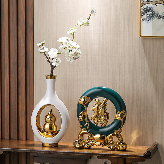 Decorative items including a white vase with gold accents and a green and gold circular ornament on a wooden surface.