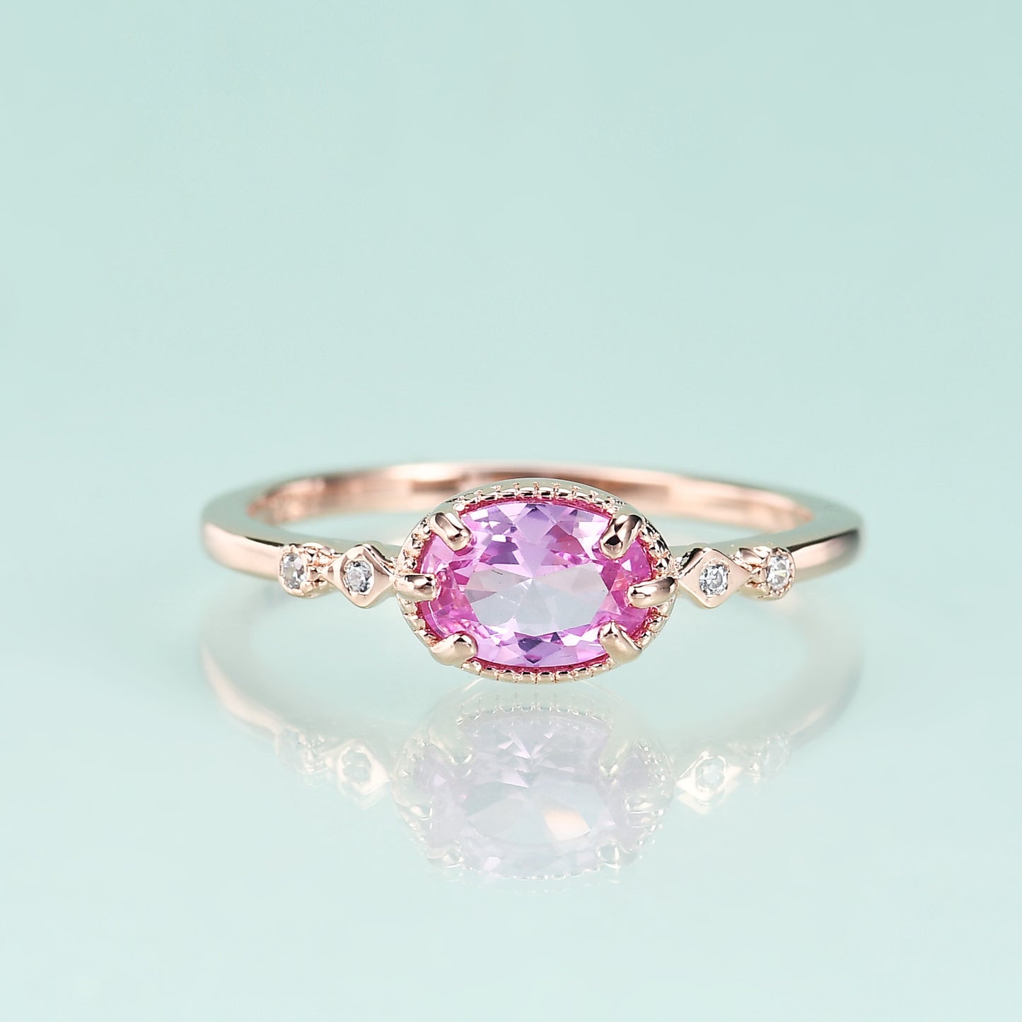 Rose gold ring with a pink gemstone on a light blue background