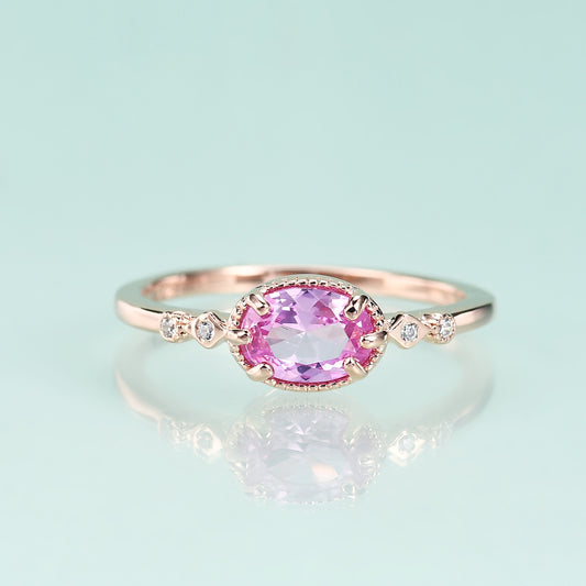 Rose gold ring with a pink gemstone on a light blue background
