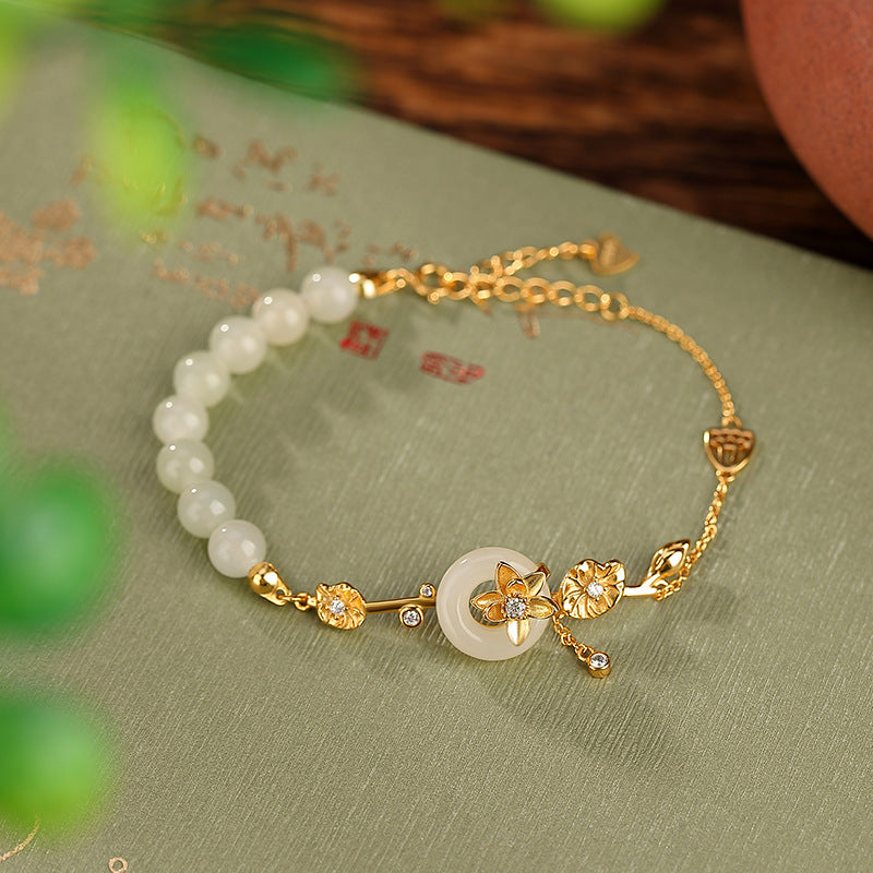 Gold bracelet with white beads on a green fabric background