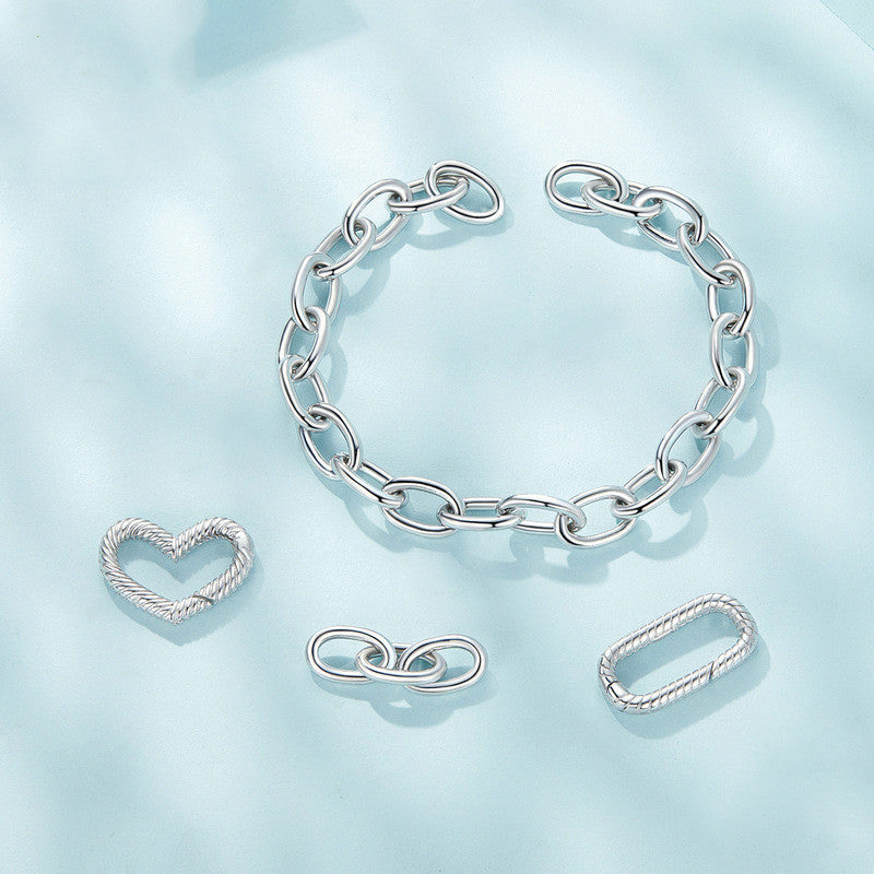 Silver bracelet, heart-shaped earring, infinity symbol earring, and rectangular ring on a light blue background