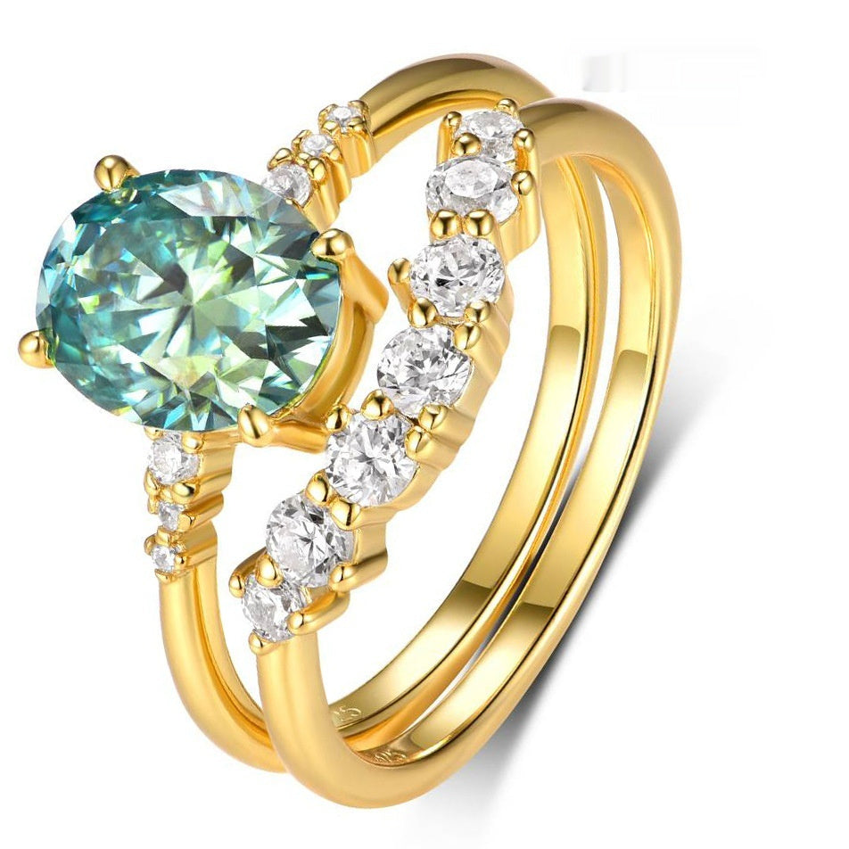 Gold ring with a large green gemstone and smaller clear stones on a white background