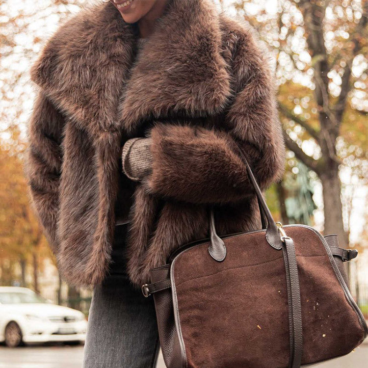 Person wearing a brown fur coat holding a matching brown leather bag on a street.