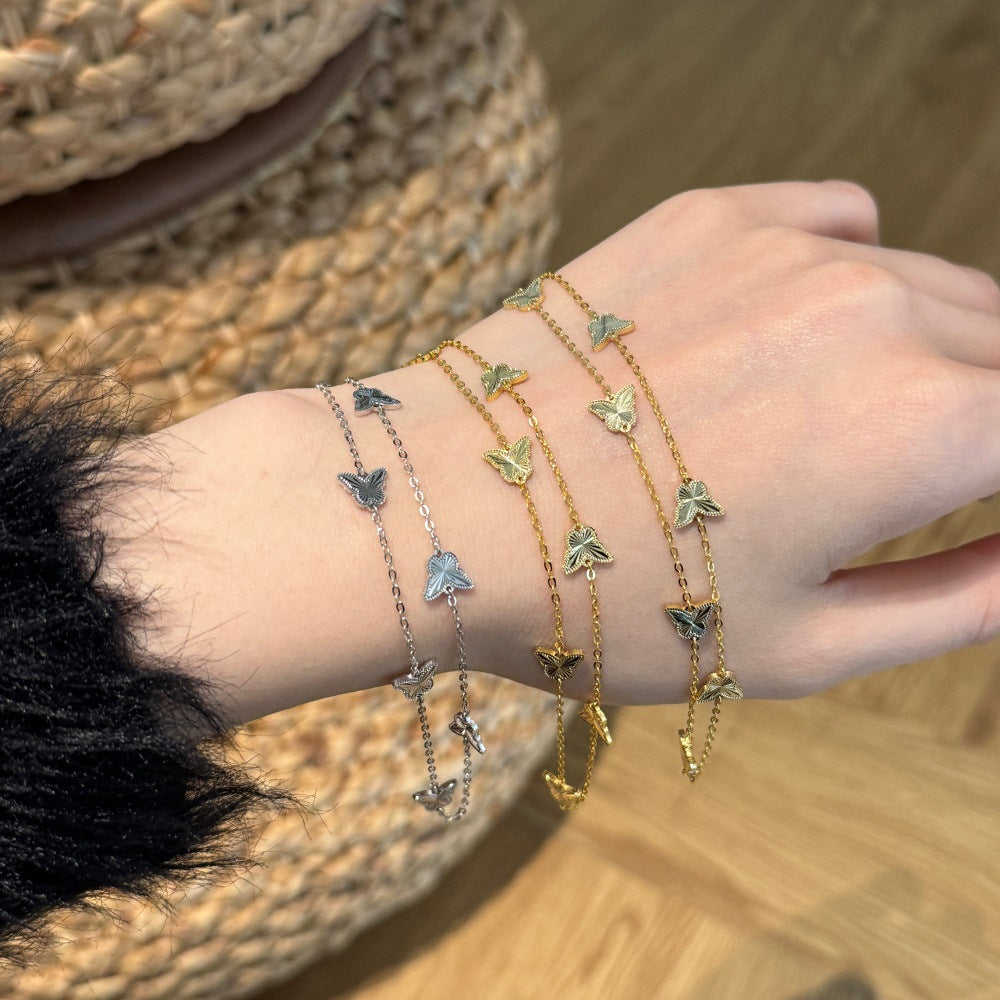 Close-up of a wrist wearing multiple butterfly-themed bracelets on a wooden surface.