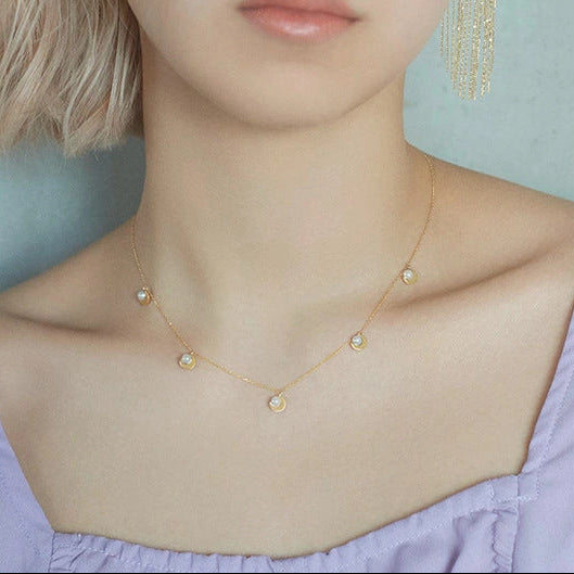 Woman wearing gold earrings and necklace against a light blue background