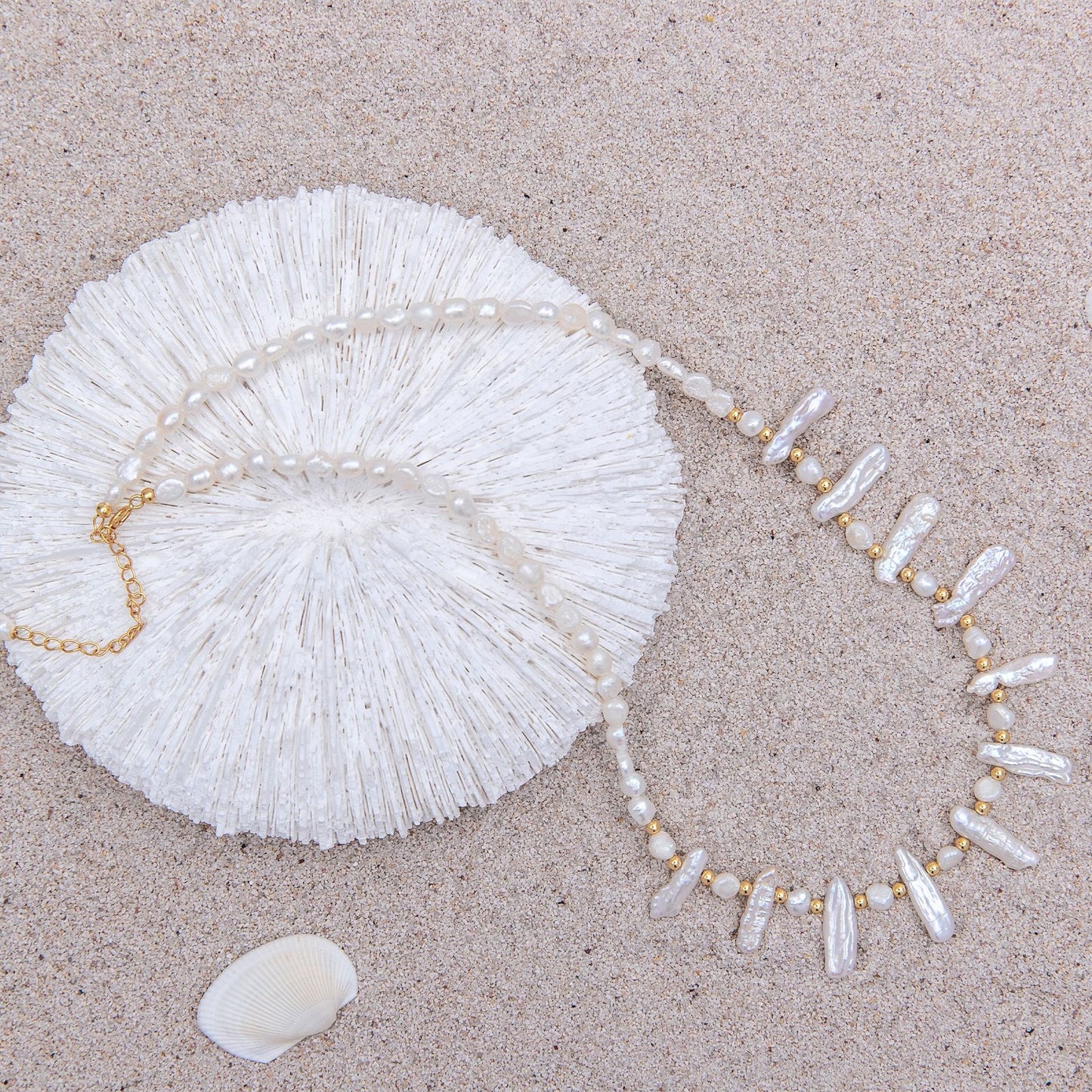 Pearl necklace and shell on a sandy surface