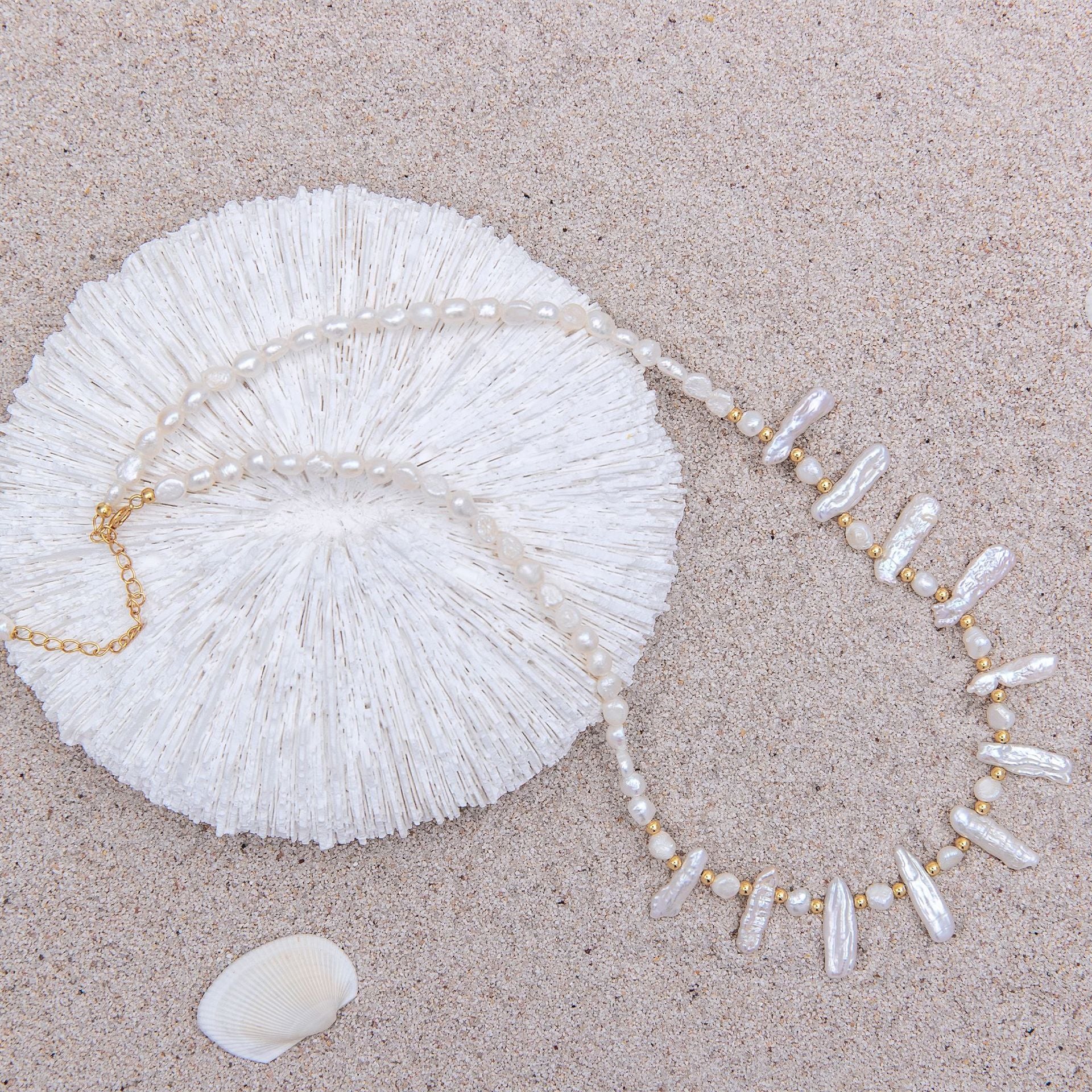 Pearl necklace and shell on a sandy surface