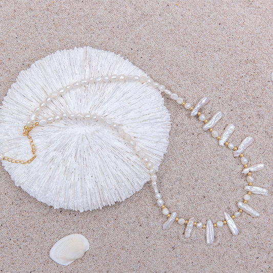 Pearl necklace and shell on a sandy surface