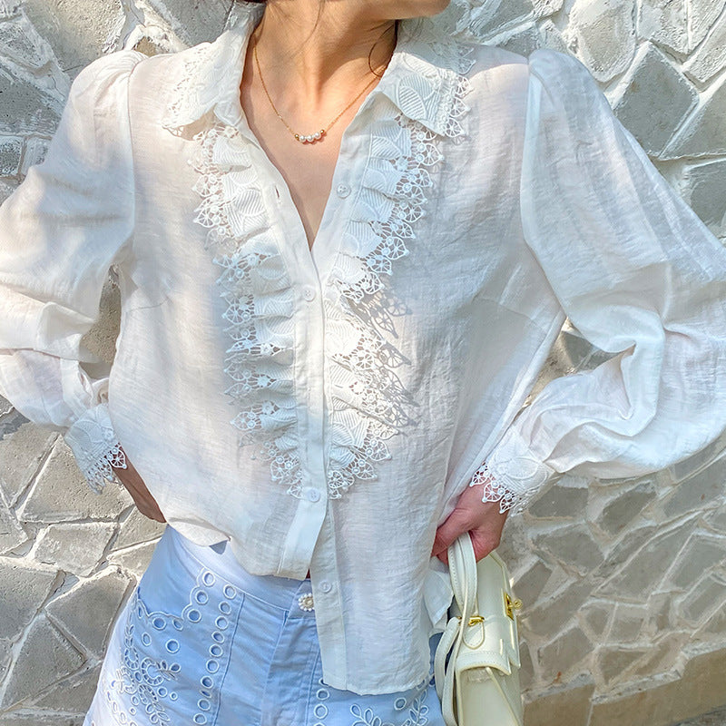 Person wearing a white lace blouse with a stone wall background