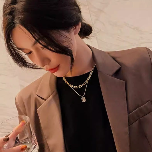 Woman in a beige blazer holding a glass with a neutral background