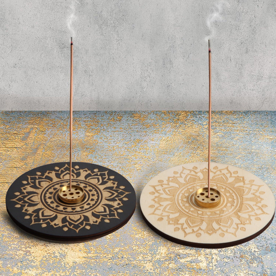 Two incense holders with mandala designs on a textured surface.