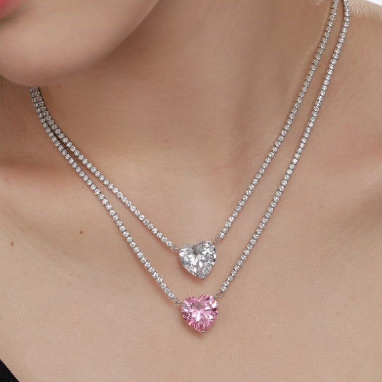 Necklace with heart-shaped pink and clear gemstones on a person's neck
