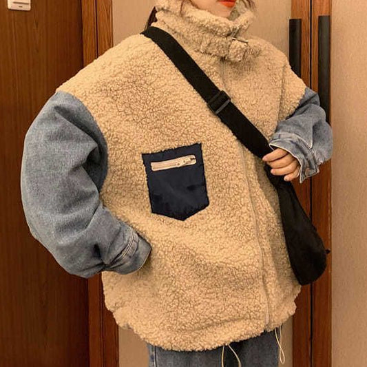 Person wearing a beige fleece vest over a blue sweater, holding a black bag indoors.