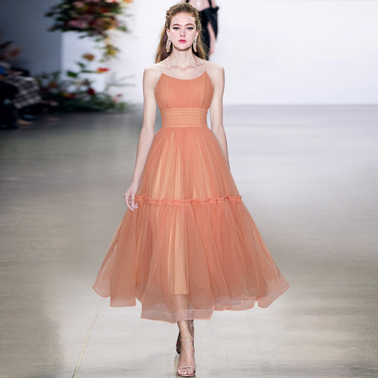 Model wearing a peach-colored dress on a runway