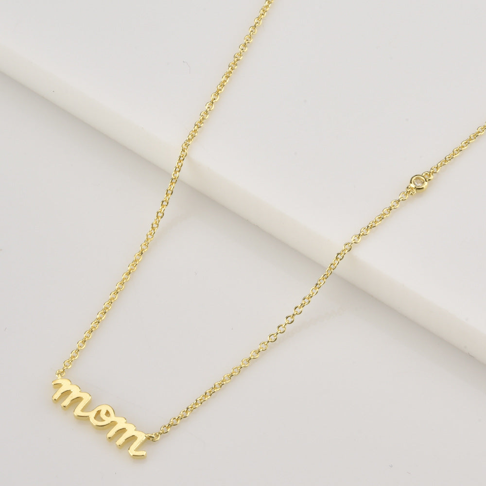 Gold necklace with 'mom' pendant on a light background