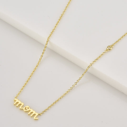 Gold necklace with 'mom' pendant on a light background