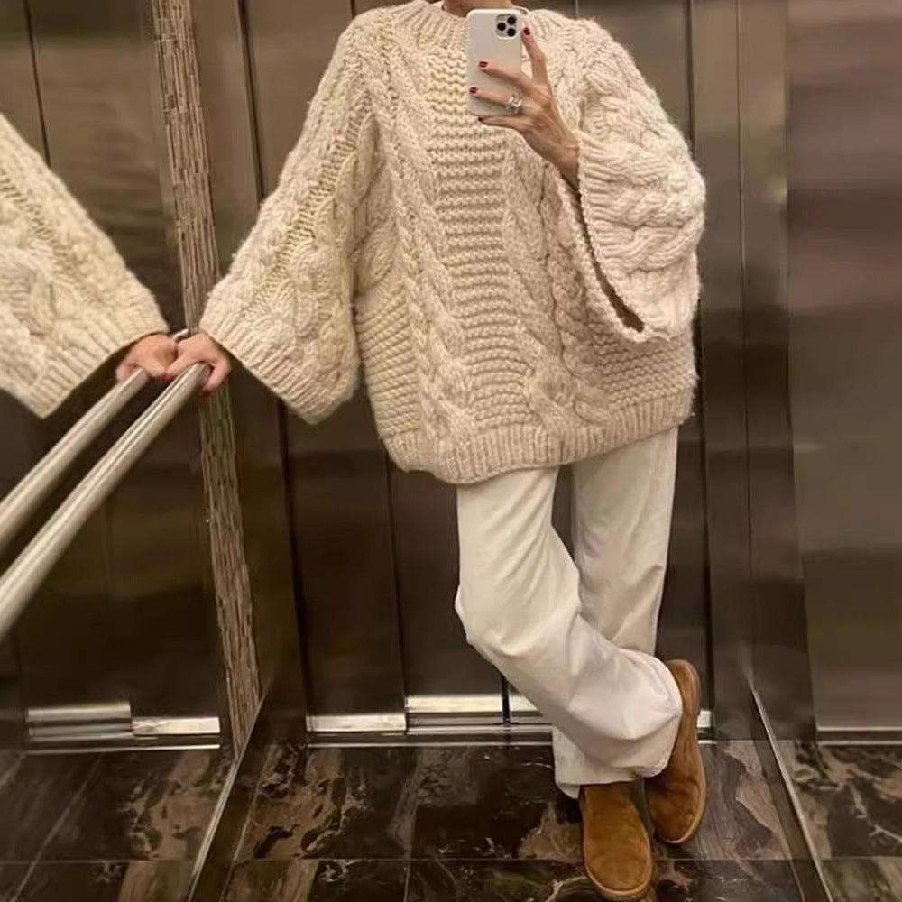 Person wearing a chunky knit sweater and white pants, standing in an elevator.