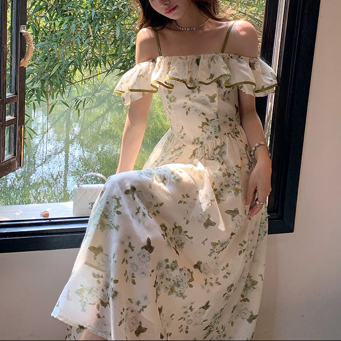 Woman in a floral dress standing by a window with greenery outside