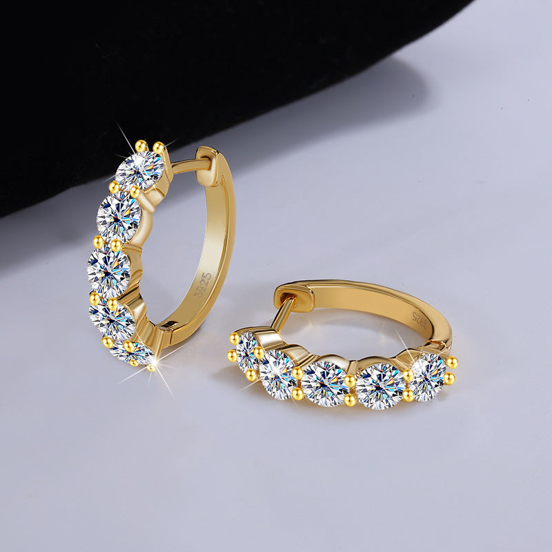 Gold hoop earrings with clear gemstones on a light gray background
