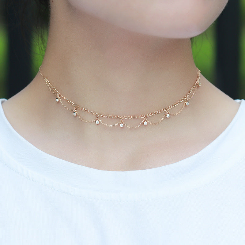 Gold necklace with small beads worn by a person on a white background