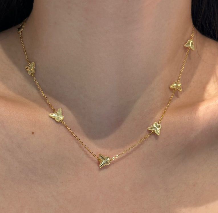 Gold necklace with butterfly pendants on a person's neck