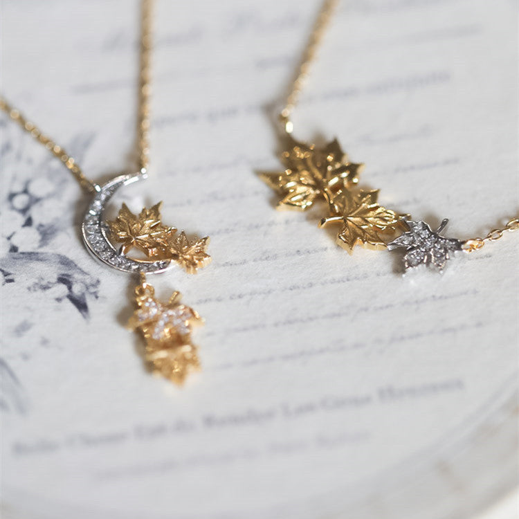 Gold necklace with leaf and moon design on a marble surface