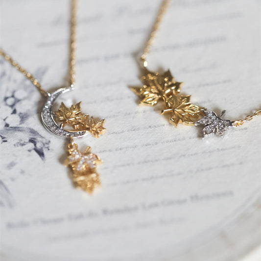 Gold necklace with leaf and moon design on a marble surface