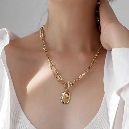 Gold necklace with a pendant worn by a person against a neutral background