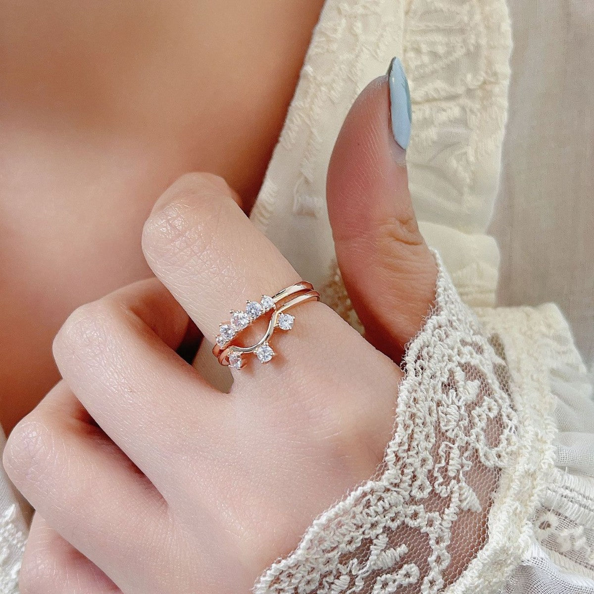 Close-up of a hand wearing two rings with a delicate lace sleeve.