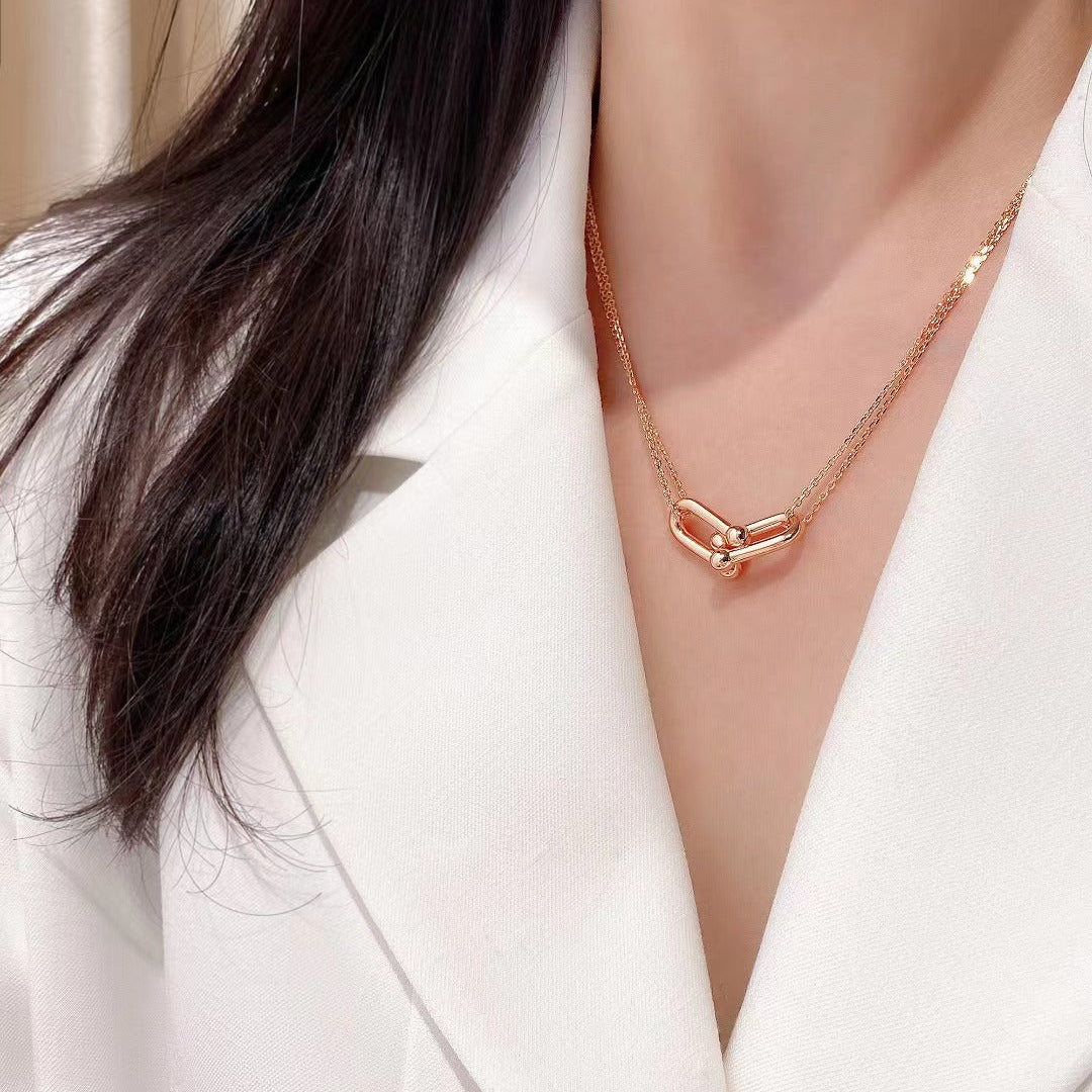 Rose gold necklace worn by a person in a white blazer
