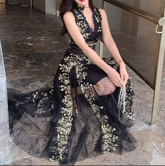 Woman in a black and gold dress sitting on a staircase indoors.