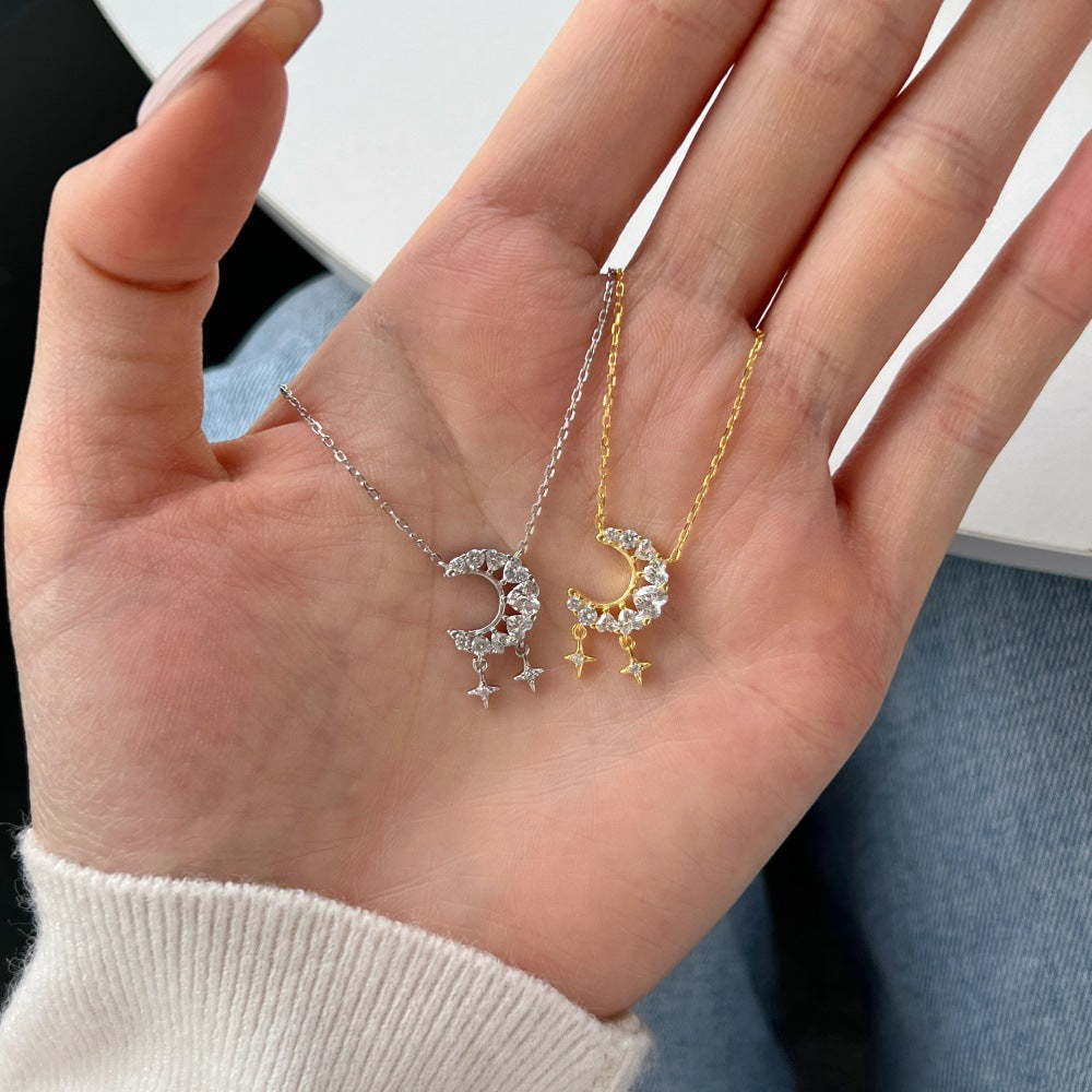 Two moon and star necklaces on a person's hand