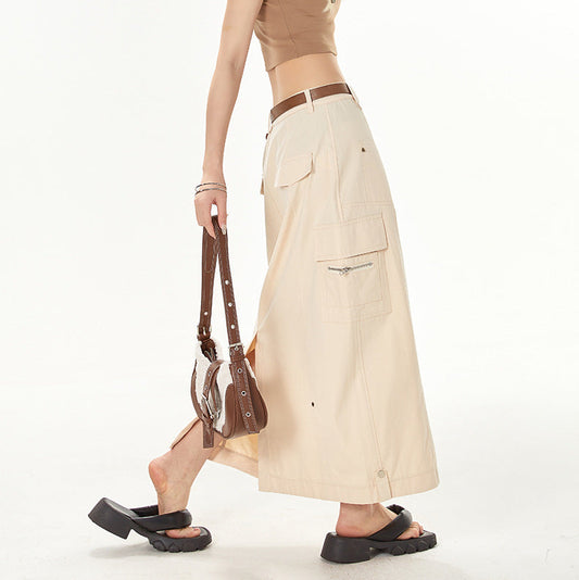 Woman wearing a brown crop top and beige skirt with sunglasses on a white background