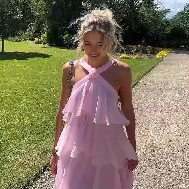 Woman in a pink dress standing on a path with trees and grass in the background