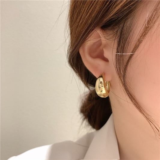 Gold hoop earring worn by a person with a neutral background