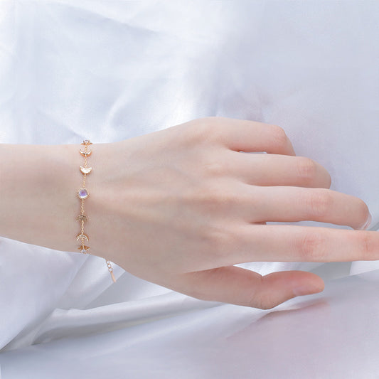 Hand wearing a delicate bracelet on a white fabric background